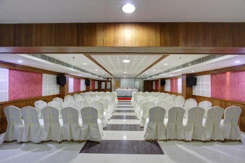 a conference room with white chairs and a table at Hotel Prince Gardens in Coimbatore
