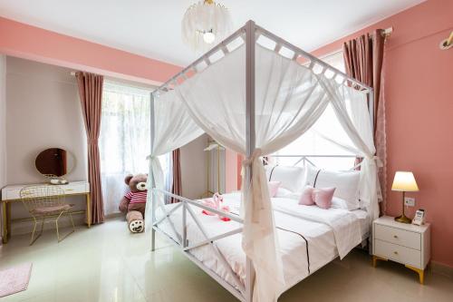 1 dormitorio con cama con dosel y paredes rosas en Summer Tree Inn (The Captain's Hostel) en Sanya