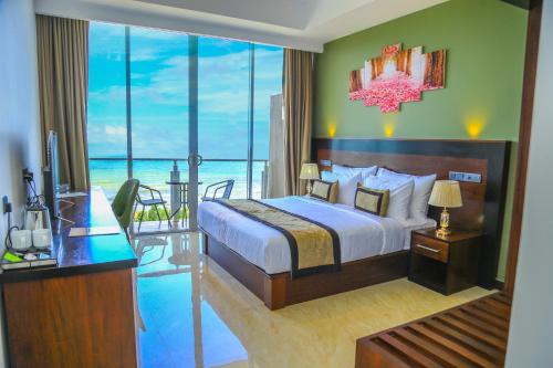 a bedroom with a bed and a view of the ocean at Ruvisha Beach Hotel in Negombo