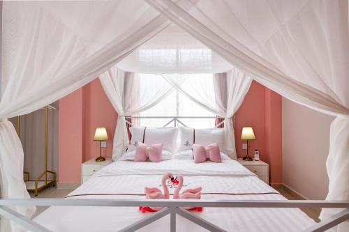 Un dormitorio con una cama blanca con almohadas rosas y una ventana en Summer Tree Inn (The Captain's Hostel) en Sanya