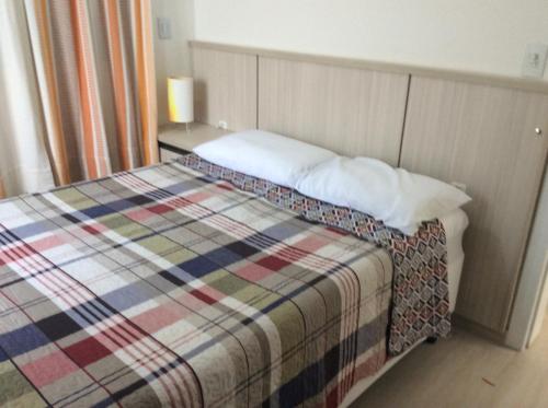 een slaapkamer met een bed met een kleurrijke deken bij Residencial Annabel APTO 02 in Bombinhas