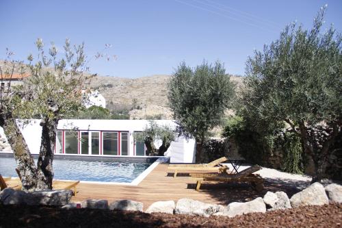 a backyard with a pool and trees and a house at Pedra Nova in Castelo Novo
