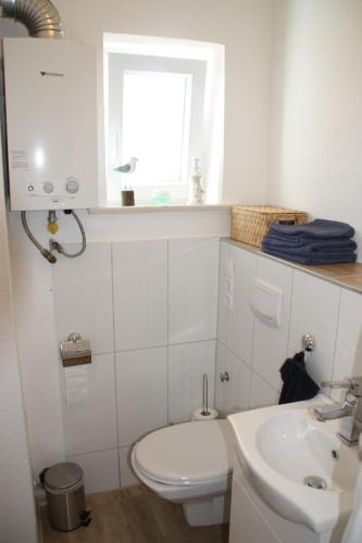 La salle de bains est pourvue de toilettes, d'un lavabo et d'une fenêtre. dans l'établissement Ferienwohnung Möwennest I, à Emden
