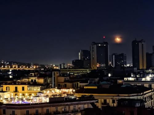 a city skyline at night with the moon in the sky at B&B Belvedere in Naples