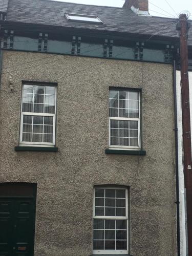a brick building with four windows and a door at City centre rooms Abercorn road ltd free parking free WiFi in Derry Londonderry