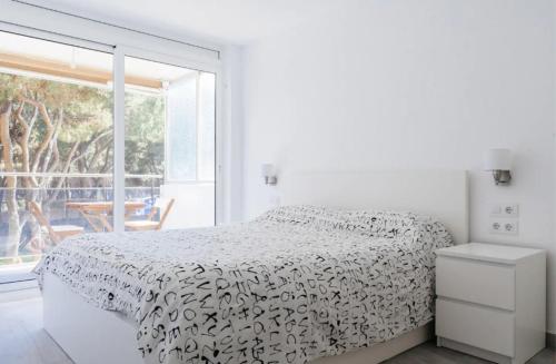 a white bedroom with a bed and a large window at Pine Paradise by Seasidehomes in Gavà