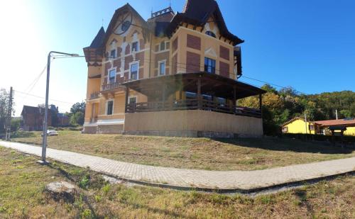 a large building on a hill with a sidewalk in front at Pensiunea Mayumi Moneasa in Moneasa