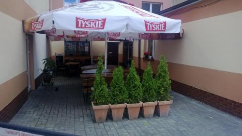 a restaurant with an umbrella and plants in front of it at Apartamenty NOCLEGI BĘDZIN in Będzin