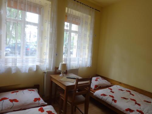 a room with two beds and a desk and windows at Apartamenty NOCLEGI BĘDZIN in Będzin