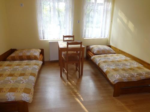 Habitación con 2 camas, mesa y ventanas. en Apartamenty NOCLEGI BĘDZIN, en Będzin