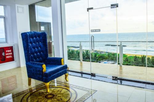 a blue chair in a room with a view of the ocean at Ruvisha Beach Hotel in Negombo