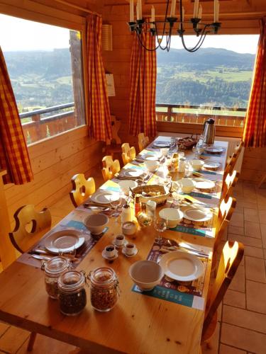 une grande table en bois avec des assiettes et de la vaisselle dans l'établissement Les Genévriers, à Foncine-le-Haut