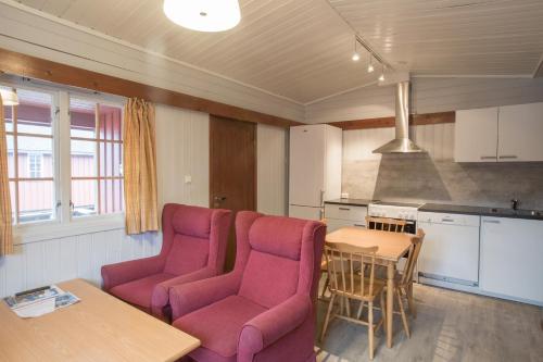 a living room with purple chairs and a table and a kitchen at Sauda Fjord Camping in Saudasjøen