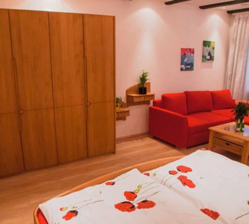 a living room with a red couch and a bed at Aufhauser Hof Regensburg in Regensburg