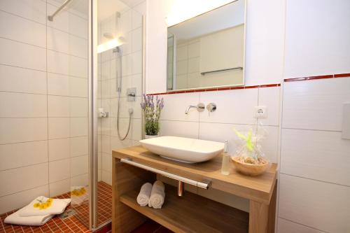 une salle de bain avec un lavabo et une douche avec un miroir dans l'établissement Landhaus Wild, à Riezlern
