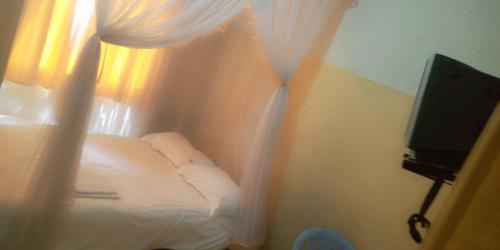 1 dormitorio con 1 cama con cortinas y TV en Hotel Jaffers Nairobi en Nairobi