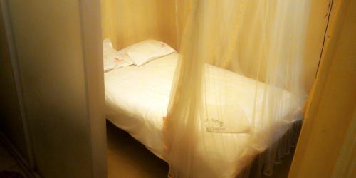 a bedroom with a bed with white curtains at Hotel Jaffers Nairobi in Nairobi
