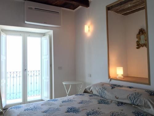 a bedroom with a bed with a mirror and a balcony at Palazzo Pizzo Studio Bellavista in Pizzo