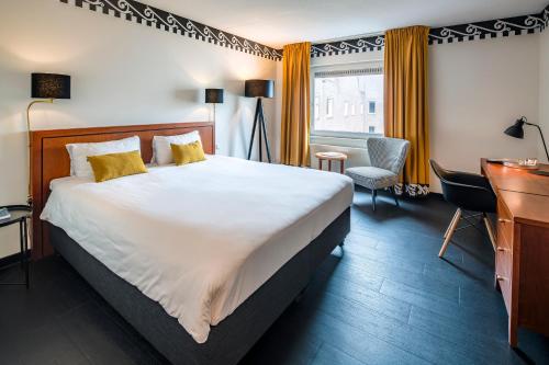 um quarto de hotel com uma cama grande e uma secretária em Hotel Theater Figi em Zeist