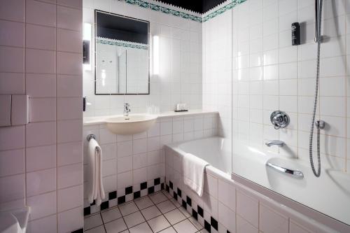 een witte badkamer met een bad en een wastafel bij Hotel Theater Figi in Zeist