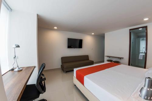 a bedroom with a bed and a couch and a tv at Altoprado Popayán in Popayan