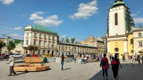 リヴィウにあるMini Smart Apartments in the central part of Lvivの時計塔のある広場を歩く集団
