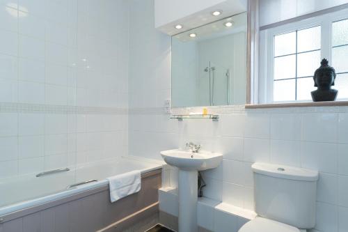 a bathroom with a sink and a toilet and a tub at Gorse Hill Hotel in Woking