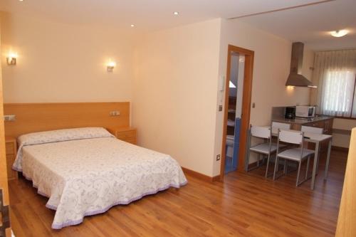 a bedroom with a bed and a table and a kitchen at Apartamentos Ay Sálvora in O Grove