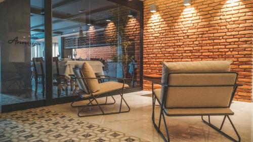 a room with two chairs and a brick wall at Annaya Suítes in Viçosa