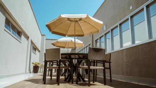 a table and chairs with an umbrella on a balcony at Annaya Suítes in Viçosa