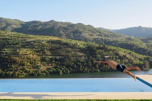 a person jumping off a diving board into a lake at Casa da Mouta - Douro Valley in Baião