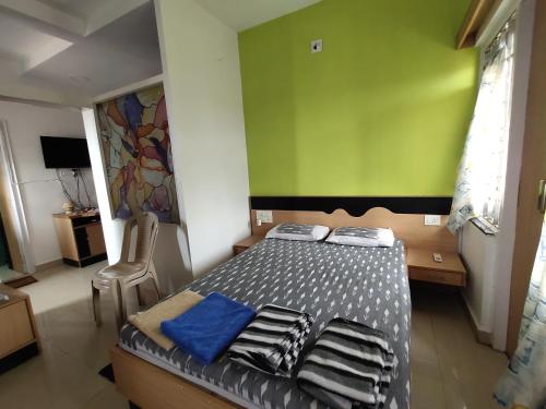 1 dormitorio con cama y pared verde en NIRMAN beach homestay, en Puri