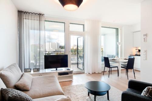 - un salon avec un canapé, une télévision et une table dans l'établissement Aallonkoti Apartments, à Helsinki