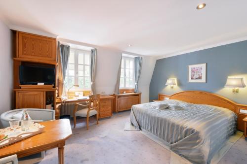 a bedroom with a bed and a desk and a table at Hotel Landhaus Wachtelhof in Rotenburg an der Wümme
