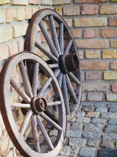 a wooden wagon wheel attached to a brick wall at Hotel Zur Linde Dein Self Check In in Michendorf