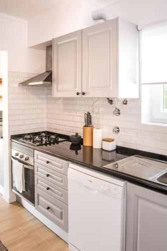 a kitchen with white cabinets and a stove top oven at Casa da Quintinha - Villa with a pool in Sesimbra