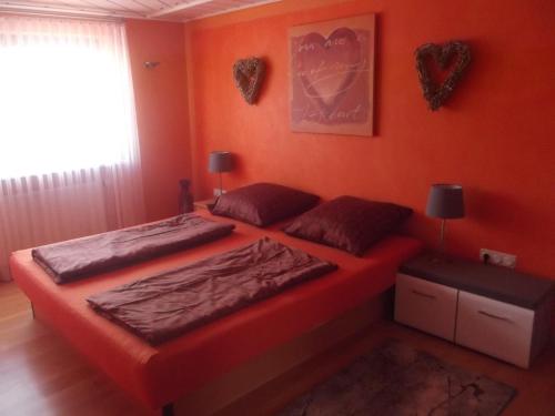 - 2 lits dans une chambre aux murs orange dans l'établissement Ferienwohnung in Puschendorf, à Puschendorf