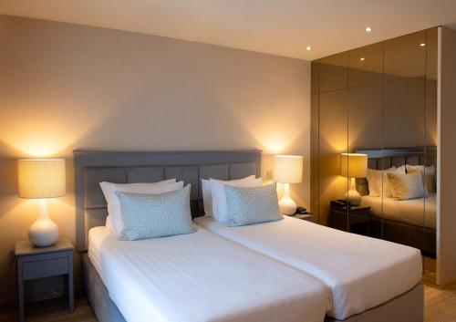 a bedroom with a bed with two lamps and a mirror at Hotel Cristal Vieira Praia & SPA in Praia da Vieira