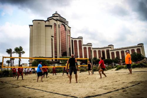 a group of people playing a game of volleyball on the beach at L’Auberge Casino Resort Lake Charles in Lake Charles