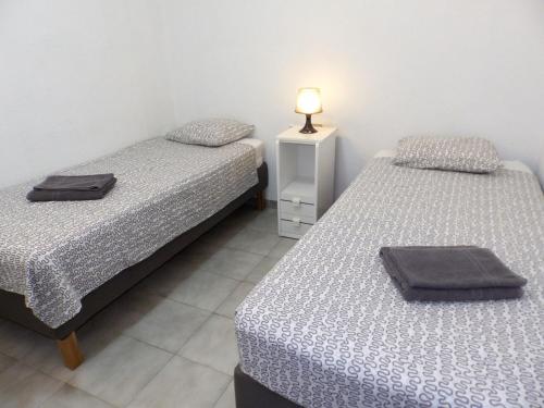 een slaapkamer met 2 bedden en een lamp op een nachtkastje bij Apartamentos Medano - Estrella del Mar in El Médano