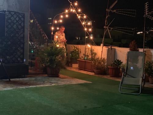 a man standing on a patio at night with lights at B&B Camelot in Palermo