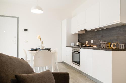 una cocina con armarios blancos y una mesa en una habitación en FCO Luxury Apartments, en Fiumicino
