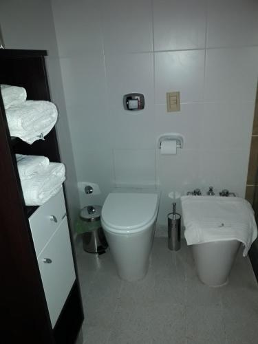 a white bathroom with a toilet and a sink at Hotel de Campo Posada la Esperanza in Río Cuarto