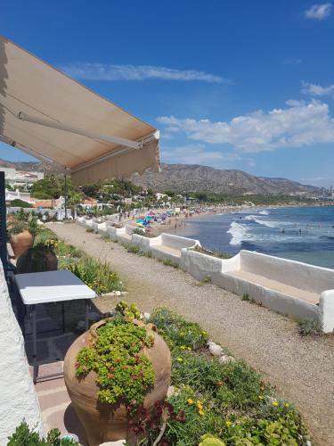 a beach with a table and chairs and the ocean at La Almadraba Experience in Platja de l’Almadrava
