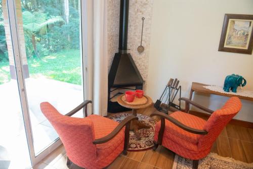 a room with two chairs and a table with a stove at Refúgio das Araucárias in Ibiúna