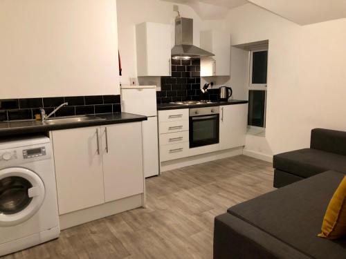 a kitchen with white cabinets and a washer at Smart central apartment, 5 mins from centre in Cardiff