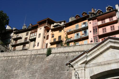 a tall building behind a wall with a building at Suite Home Briancon Serre Chevalier in Briançon