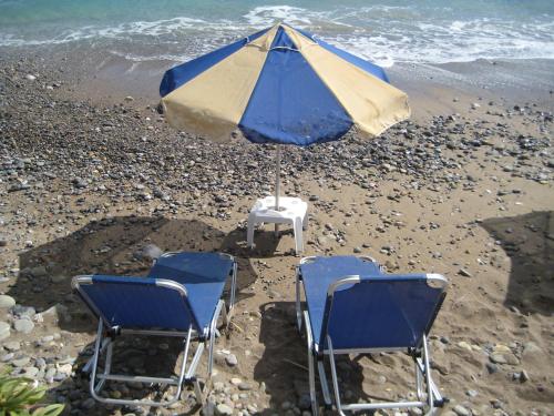 two chairs and an umbrella on a beach at Coral Front Beach in Káto Zákros