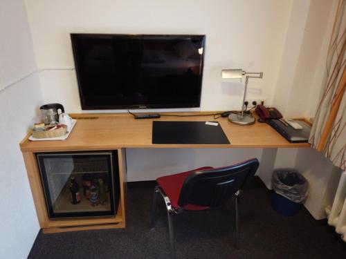 a desk with a computer and a television on it at BB City Hotel in Böblingen