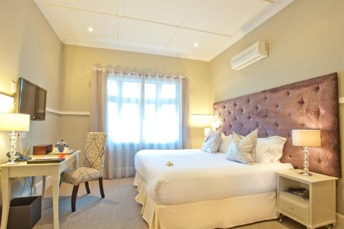 Schlafzimmer mit einem Bett, einem Schreibtisch und einem Fenster in der Unterkunft Saint James on Venice in Durban